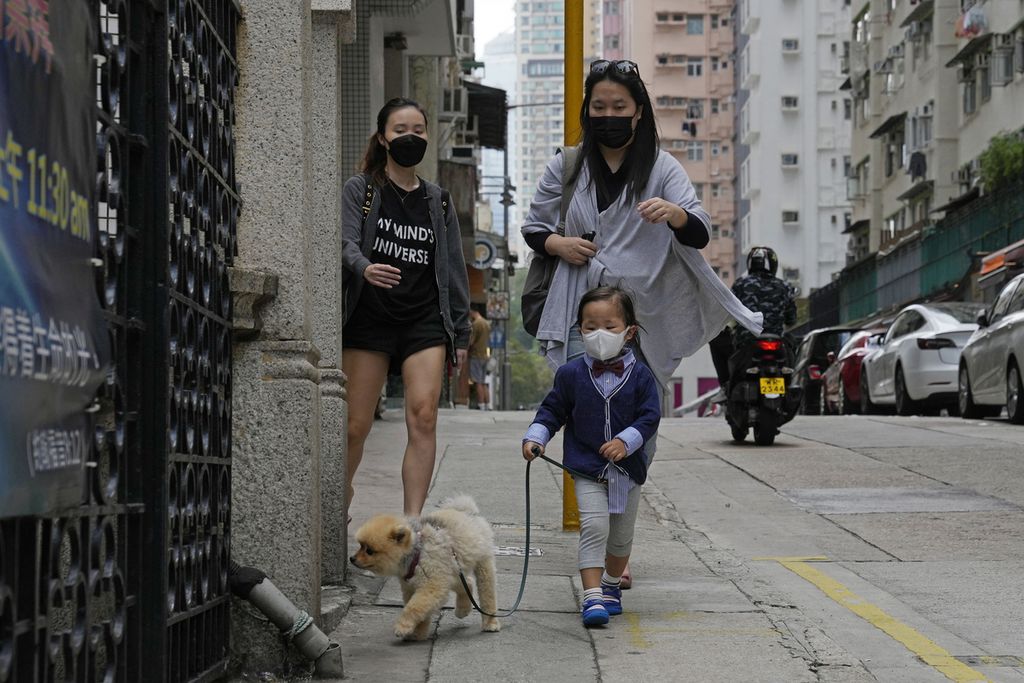 Seorang anak membawa jalan-jalan anjingnya di Hong Kong, MInggu (13/3/2022). 