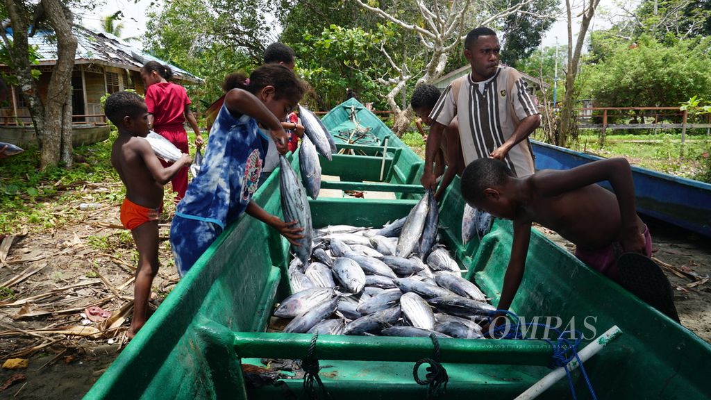 Anak-anak dan sejumlah masyarakat adat Biak Karon mengambil hasil tangkapan ikan dari nelayan yang sebagian sudah dipindahkan ke rumah warga di Kampung Werur, Distrik Bikar, Kabupaten Tambrauw, Papua Barat Daya, Jumat (24/3/2023). 