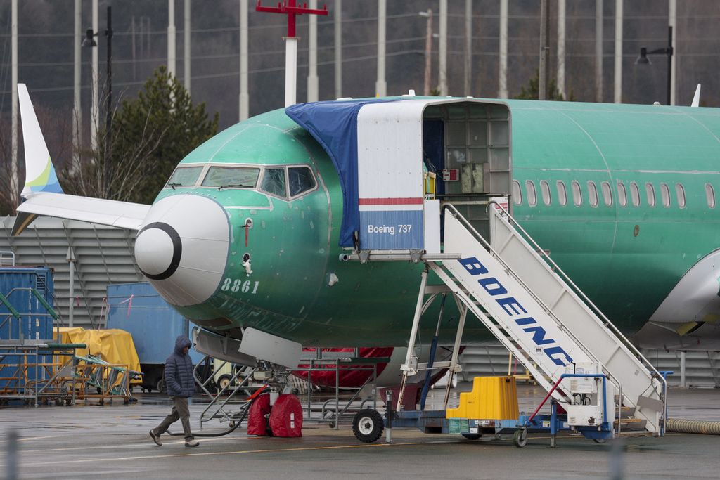 A worker passes a Boeing 737-8 MAX plane parked at a Boeing factory in Renton, Washington, January 25, 2024.