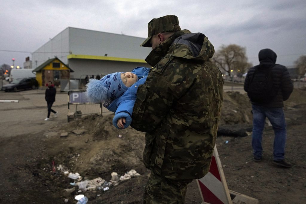 Seorang tentara Polandia menggendong bayi seorang pengungsi Ukraina setibanya di perbatasan di Medyka, Polandia tenggara, Rabu (2/3/2022).