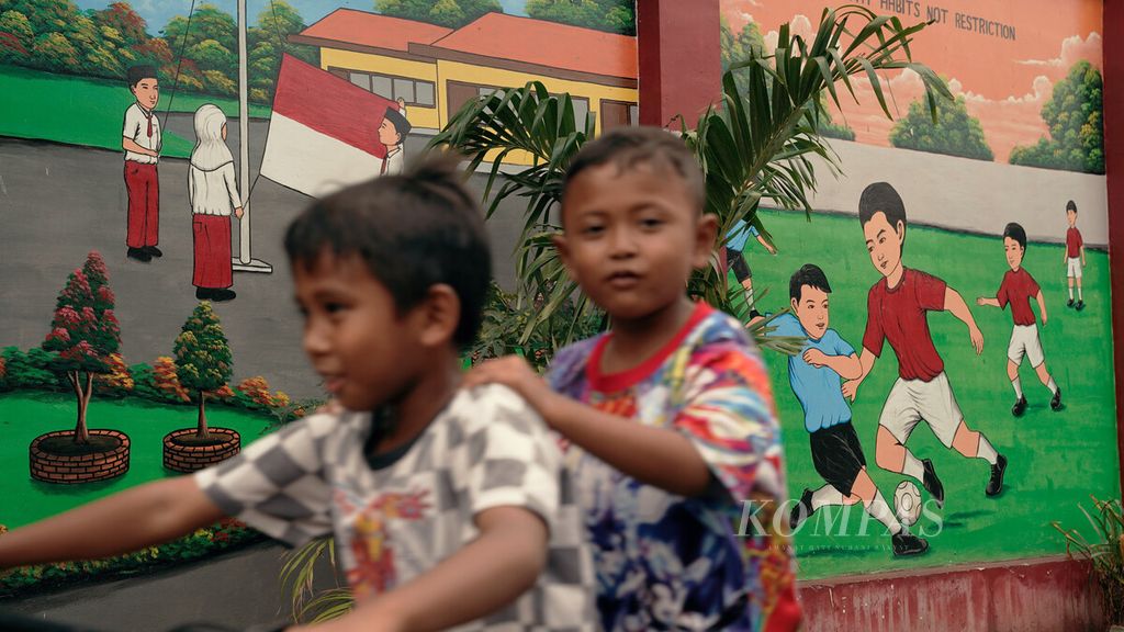 Anak-anak melintasi mural yang menghiasai gedung sekolah dasar di Sukapura, Cilincing, Jakarta Utara, Senin (14/3/2022). 