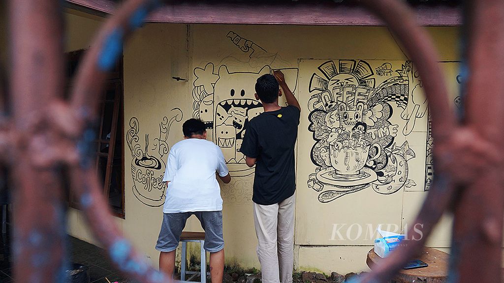 Pemuda Desa Tanggul, Kecamatan Tanggul, Jember, Jawa Timur, menggambari dinding rumah yang disulap menjadi kafe.