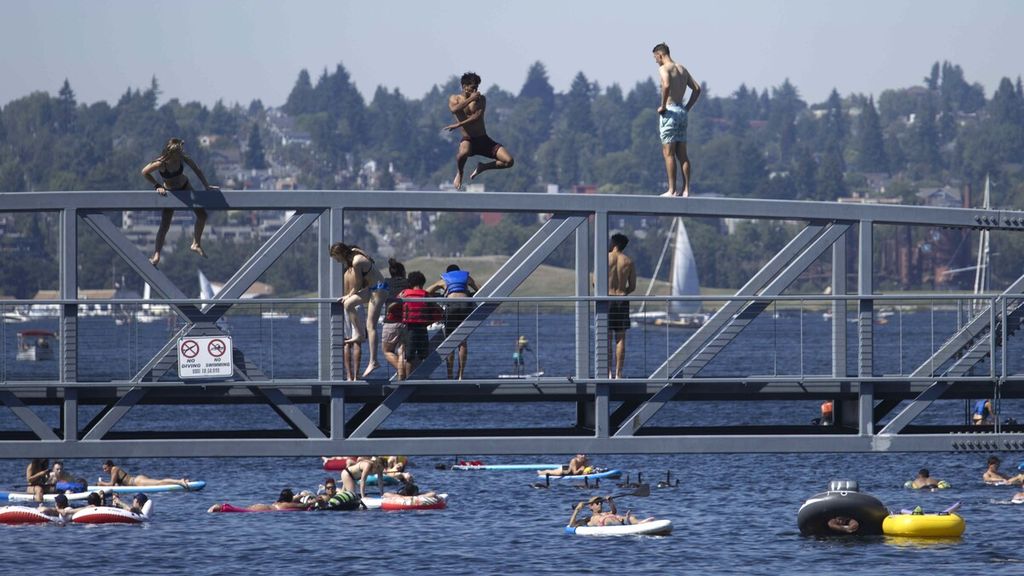 Warga beramai-ramai memanjat jembatan untuk menceburkan diri ke Danau Union di Seattle, Washington, Amerika Serikat (AS), saat gelombang panas menerjang kawasan Pasifik Barat Laut (AS), Minggu (27/6/2021). 