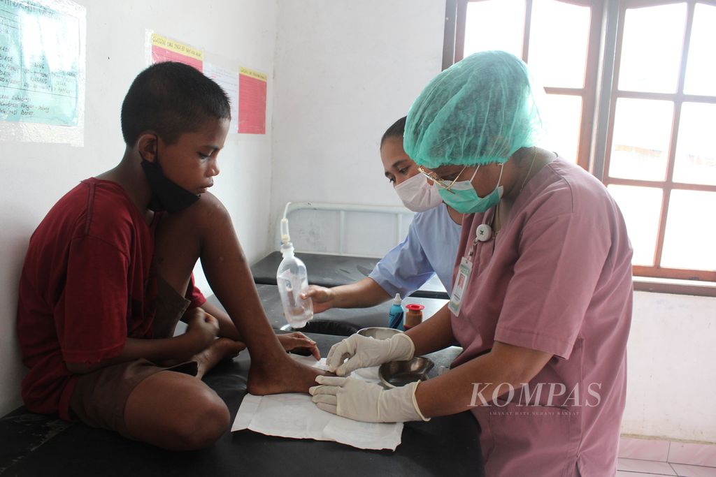 Perawat membersihkan luka kaki anak yang terdampak erupsi Gunung Lewotobi Laki-laki di pos kesehatan Desa Pululera, Kecamatan Wulanggitang, Kabupaten Flores Timur, Nusa Tenggara Timur, Jumat (5/1/2023). Erupsi terus terjadi selama dua minggu terakhir.