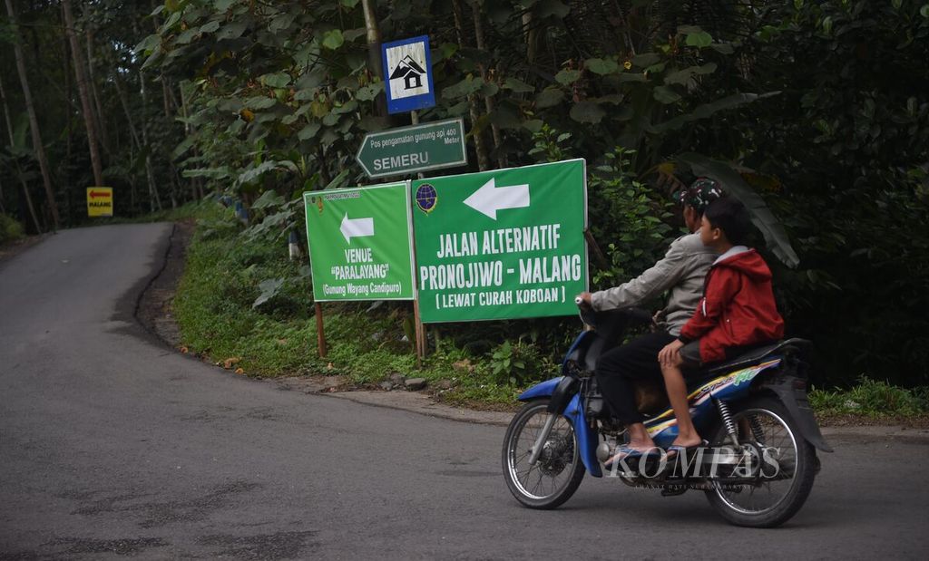Warga melewati Jalan Alternatif Lumajang-Malang di Kecamatan Candipuro, Kabupaten Lumajang, Senin (11/7/2022). Jalan alternatif tersebut melewati Besuk Kobokan yang merupakan aliran lahar Gunung Semeru. 