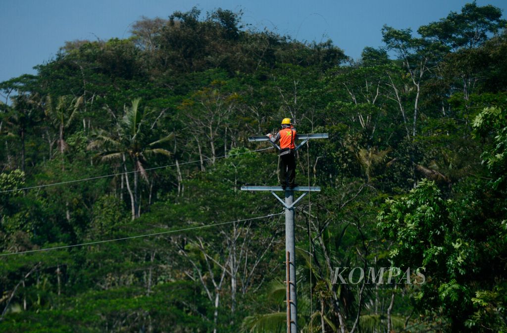 Pekerja memasang instalasi di atas tiang listrik di kawasan pedesaan di Kecamatan Pingit, Kabupaten Temanggung, Jawa Tengah, Jumat (26/7/2019). 