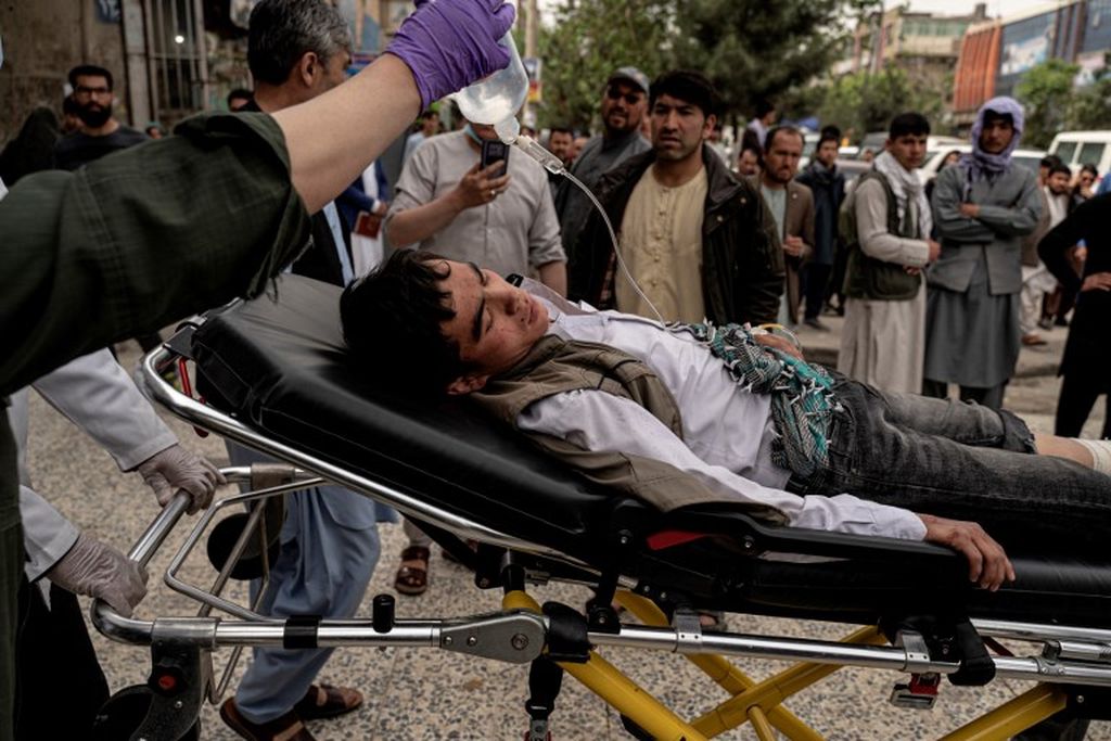 Petugas medis memindahkan seorang pemuda yang terluka dengan tandu di luar sebuah rumah sakit di Kabul, Selasa (19/4/2022), setelah dua ledakan bom mengguncang sekolah anak laki-laki di lingkungan Syiah Hazara yang menewaskan sedikitnya enam orang. 