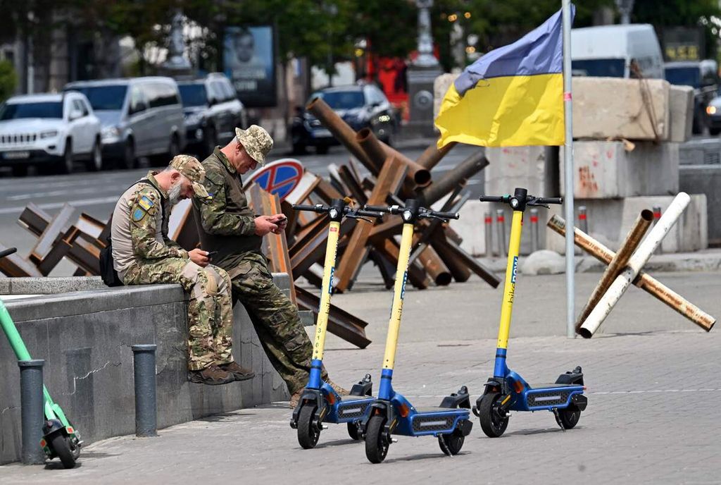 Prajurit Ukraina tengah memainkan telepon selular mereka ketika beristirahat di sebuah jalan di kota Kyiv, Rabu (22/6/2022).