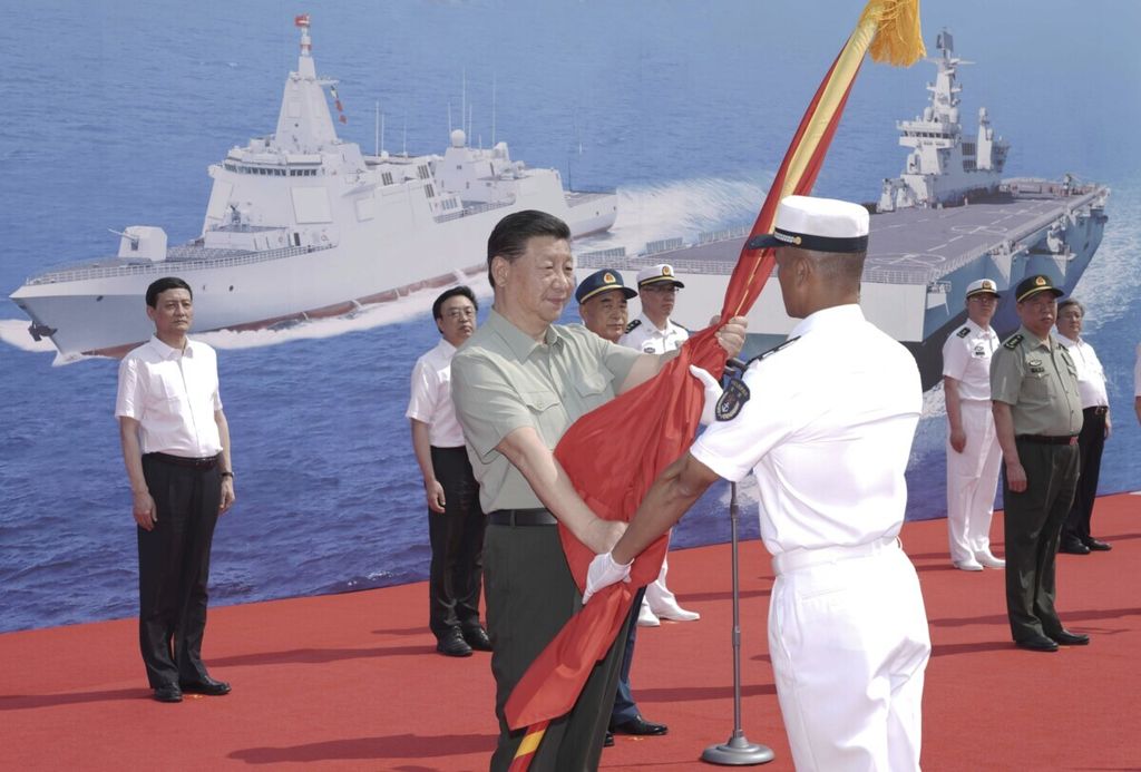 Foto yang dirilis Kantor Berita China, Xinhua, menunjukkan Presiden China Xi Jinping menyerahkan bendera Tentara Pembebasan Rakyat kepada kapten Kapal Hainan di Sanya, Provinsi Hainan, China, Sabtu (24/4/2021). (Li Gang/Xinhua via AP)