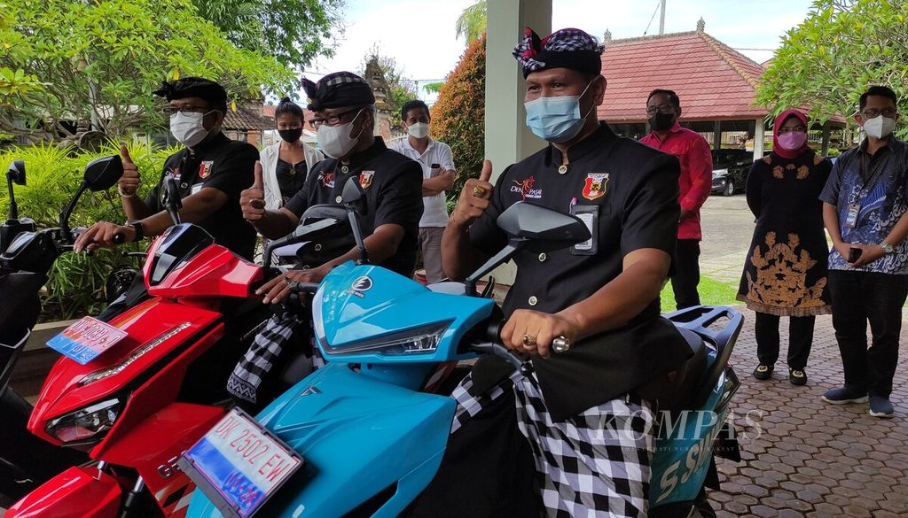 Tiga <i>pacalang</i> (pengamanan swakarsa desa adat) dari Pasikian Pacalang Kota Denpasar menjajal sepeda motor listrik di Kantor Dinas Perhubungan Provinsi Bali, Kota Denpasar, Jumat (25/2/2022). 