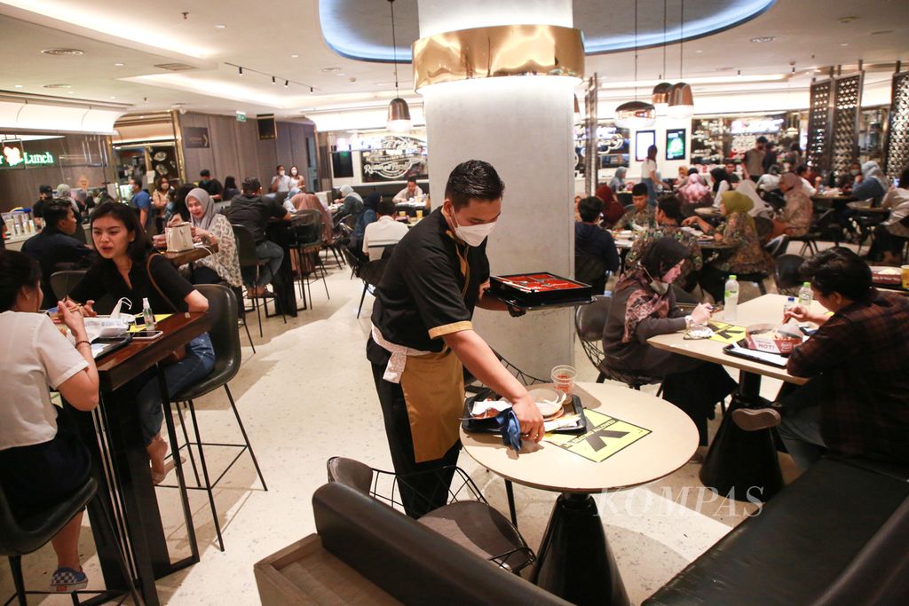 Petugas membersihkan meja yang telah digunakan pengunjung saat jam buka puasa di <i>food court </i>Senayan City Mal, Jakarta, Rabu (13/4/2022). Para petugas ini hanya sempat membatalkan puasa seadanya demi melayani pengunjung yang ramai pada waktu buka puasa.
