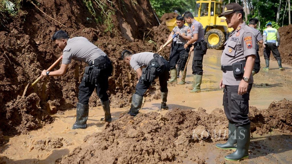Polisi membantu menyingkirkan tanah di lokasi longsor di Desa Krasak, Salaman, Magelang, Jawa Tengah (19/1/2019). Meskipun tidak menimbulkan korban jiwa namun peristiwa tanah longsor itu mengakibatkan jalan raya penghubung Magelang dengan Purworejo terputus.