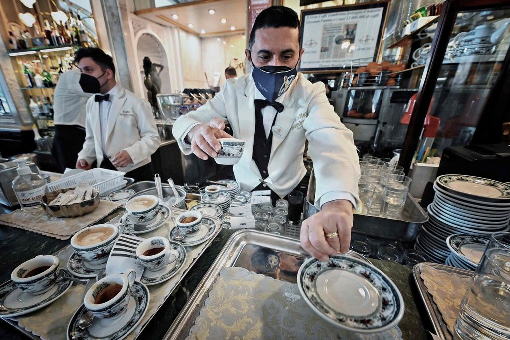Seorang pramusaji tengah menyajikan kopi espresso di Gran Caffe Gambrinus, sebuah kafe bersejarah di Naples pada Minggu (13/2/2022). Kafe itu didirikan pada 1860. Secangkir espresso bukna sekadar minuman. Espresso adalah ritual sosial dan budaya berharga yang dianggap Italia sebagai warisan nasional yang layak mendapatkan status warisan budaya tak benda dari UNESCO.