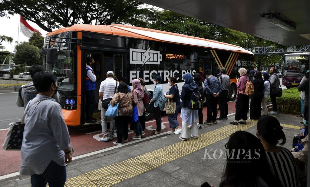 Pekerja kantor bergegas naik ke bus listrik Transjakarta di Halte Senayan, Jakarta, saat jam pulang kerja, Selasa (28/3/2023).