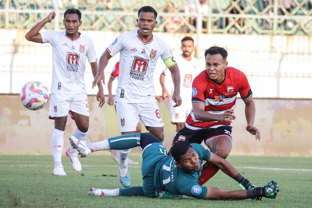 Pemain Madura United, Koko Ari Araya (kanan), menendang bola yang berusaha dihadang kiper Malut United, M Fahri (kedua dari kanan), pada pertandingan BRI Liga 1 di Stadion Gelora Bangkalan, Bangkalan, Jawa Timur, Sabtu (10/8/2024). Pertandingan berakhir imbang dengan skor 1-1.