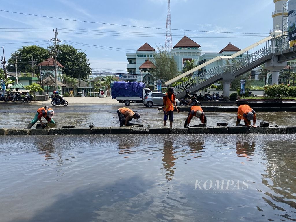 Sejumlah petugas membenahi median jalan yang berserak akibat banjir yang menggenangi Jalan Pantura Kaligawe, Kota Semarang, Jawa Tengah, Senin (8/4/2024). 
