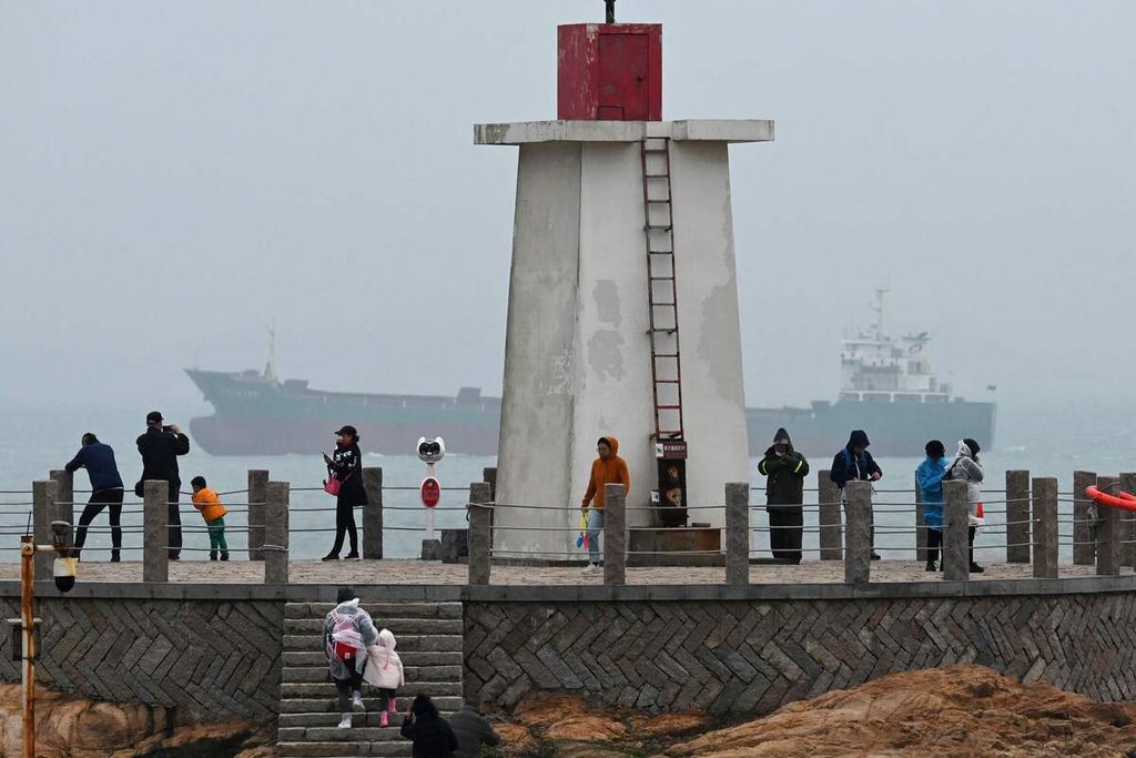 Sebuah kapal kargo terlihat berlayar di Selat Taiwan, sementara para turlis menikmati pemandangan di Pulai Pingtan, titik terdekat wilayah China dengan Taiwan, di Provinsi Fujian, China tenggara, Kamis (6/4/2023). 