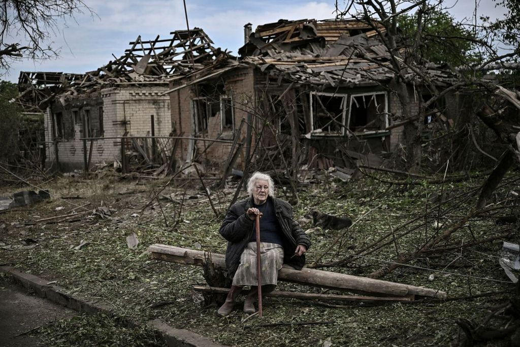 Seorang perempuan lanjut usia duduk di depan rumah yang hancur dihantam rudal di kota Druzhkivka (Druzhkovka) di wilayah Ukraina timur pada 5 Juni 2022.