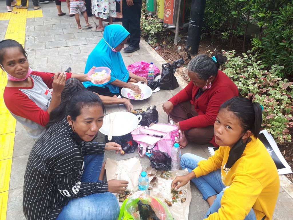 Warga yang berunjuk rasa menuntut bantuan sosial sedang makan siang di Kantor Pemerintah Provinsi DKI Jakarta, Jakarta Pusat, Rabu (14/12/2022).