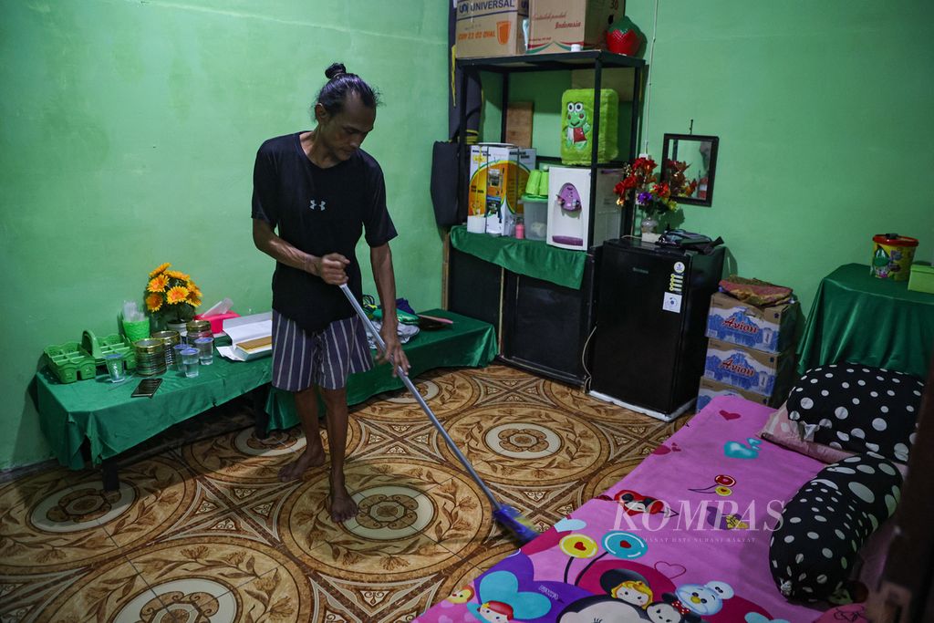 Jhon Pebri (43) menyapu lantai di Selter Ragam Berdaya Indonesia, Jakarta Barat, Jumat (12/4/2024). Selter yang berdiri sejak 2023 ini menjadi tempat singgah para transpuan yang membutuhkan tempat tinggal sementara. 