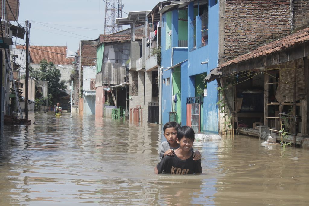 Dua anak melintasi banjir di Desa Dayeuhkolot, Kecamatan Dayeuhkolot, Kabupaten Bandung, Jawa Barat, Selasa (25/5/2021). Banjir yang menggenangi sejumlah desa di Kabupaten Bandung ini merendam lebih dari 8.500 rumah dengan ketinggian hingga 150 sentimeter.