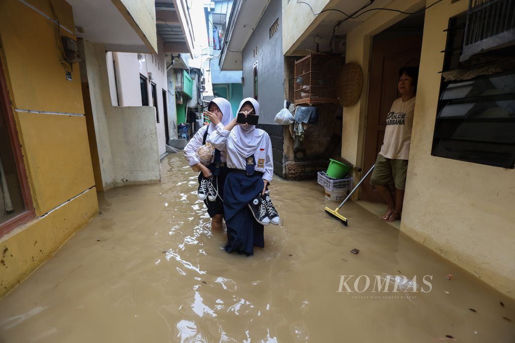 Dua siswa harus menerjang banjir di Kelurahan Kampung Melayu, Kecamatan Jatinegara, Jakarta Timur, Kamis (30/11/2023). Sejumlah daerah di DKI Jakarta tergenang banjir akibat hujan deras yang mengguyur sejak Rabu (29/11/2023) malam. 