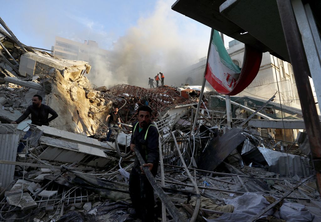 Sejumlah petugas penyelamat mengangkat puing reruntuhan bangunan yang hancur akibat serangan udara Israel di Damaskus, Suriah, Senin (1/4/2024).