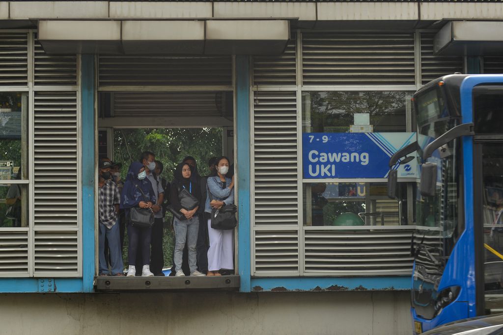 Sejumlah warga menunggu bus Transjakarta di Halte Cawang UKI, Jakarta Timur, Senin (9/1/2023).