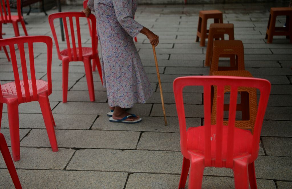Warga melintasi deretan kursi yang telah diatur secara berjarak saat pembagian angpao di Klenteng Tay Kak Sie, Pecinan, Kota Semarang, Jawa Tengah, Jumat (22/1/2021). Angpao ini sebagai bentuk bantuan kepada warga tidak mampu yang dibagikan menjelang Imlek.