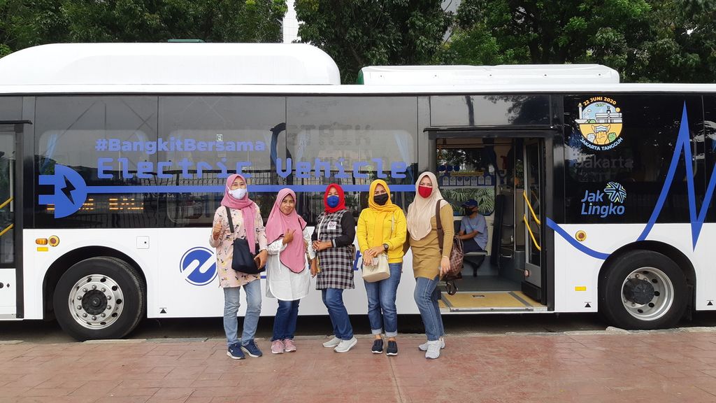 Penumpang berfoto di depan bus listrik Transjakarta, Selasa (14/7/2020).