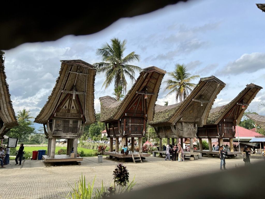 Pengunjung duduk menikmati suasana kompleks Tongkonan berusia ratusan tahun di obyek wisata Ke’te Kesu, Toraja Utara, Sulawesi Selatan, Selasa (28/12/2021).