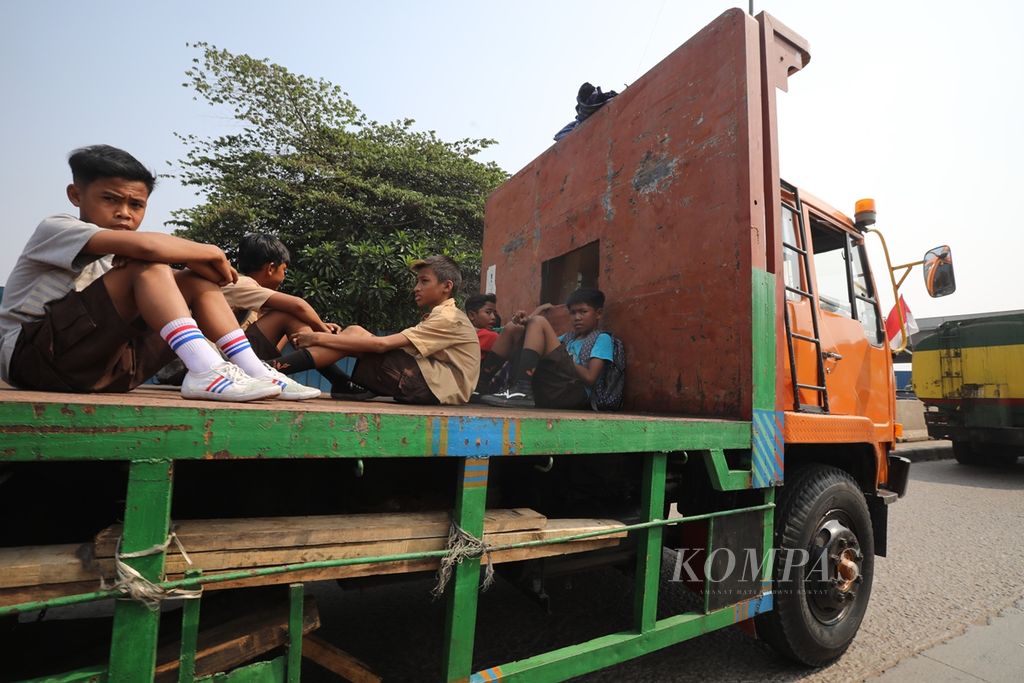 Sejumlah pelajar nekat menumpang truk kontainer yang melintas di Jalan Akses Marunda, Jakarta Utara, Rabu (18/9/2019).