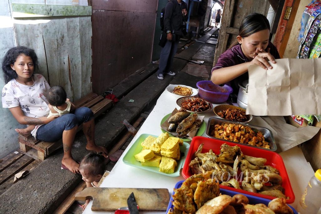 Warga menunggui dagangannya di depan rumahnya yang berada di dalam kawasan hunian semipermanen padat penduduk di Pademangan, Jakarta Utara, Kamis (17/7/2023). Badan Pusat Statistik mencatat, tingkat kemiskinan per Maret 2023 menurun dibandingkan dengan kondisi September 2022. 