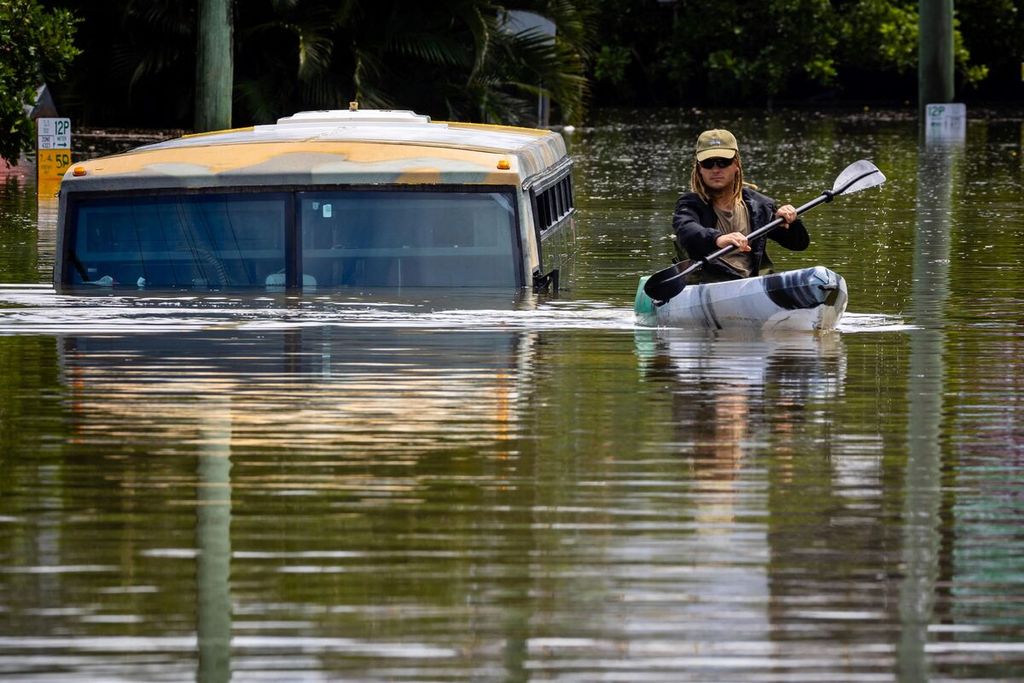 Seorang warga menggunakan kayak melintasi banjir di Milton, sebuah wilayah penyangga di pinggiran Brisbane, pada Senin (28/2/2022). 
