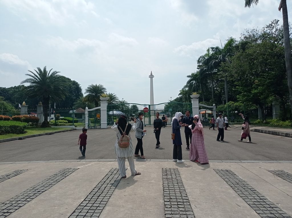 Wisatawan berswafoto di muka pintu masuk Monumen Nasional, Jakarta yang masih tutup untuk umum karena pandemi Covid-19, Rabu (4/5/2022).