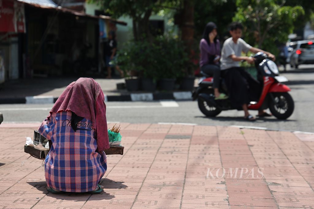 Penjual sate melindungi kepalanya dengan kain saat cuaca panas terik di Kecamatan Kraton, Yogyakarta, Sabtu (4/5/2024).
