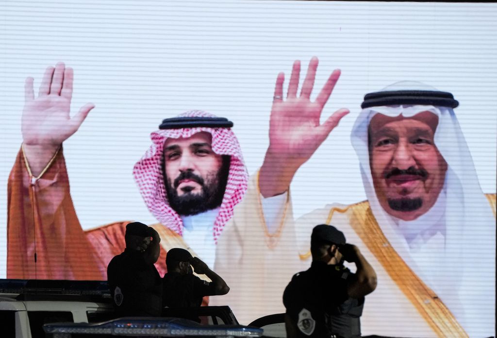 Beberapa orang anggota militer Arab Saudi mengambil gambar dua generasi Kerajaan Arab Saudi, yaitu Putra Mahkota Pangeran Mohammed bin Salman (Kiri) dan Raja Salman, yang tertera di sebuah layar raksasa di sudut Kota Mekkah, Arab Saudi, Minggu (3/7/2022).