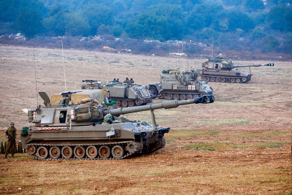 Tentara Israel bersenjatakan meriam artileri menjaga posisi mereka di lokasi yang dirahasiakan di Israel utara yang berbatasan dengan Lebanon, Minggu (8/10/2023).  