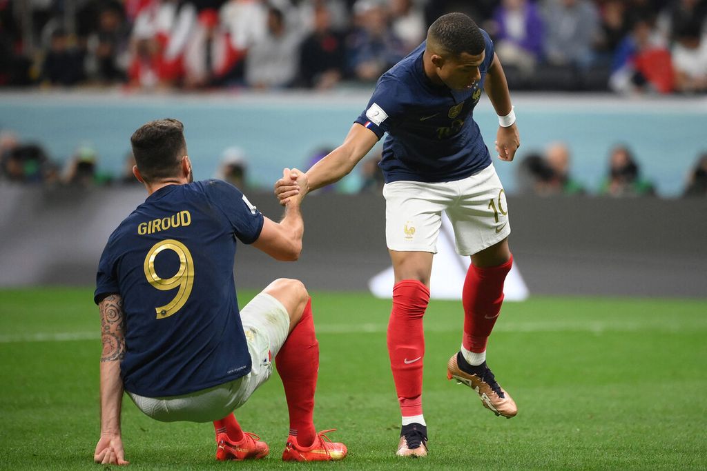 Penyerang Perancis, Kylian Mbappe (kanan), membantu rekannya, Olivier Giroud, bangkit saat laga perempat final Piala Dunia Qatar 2022 antara Inggris dan Perancis di Stadion Al-Bayt di Al Khor, utara Doha, Qatar (10/12/2022). Perancis menang, 2-1. 