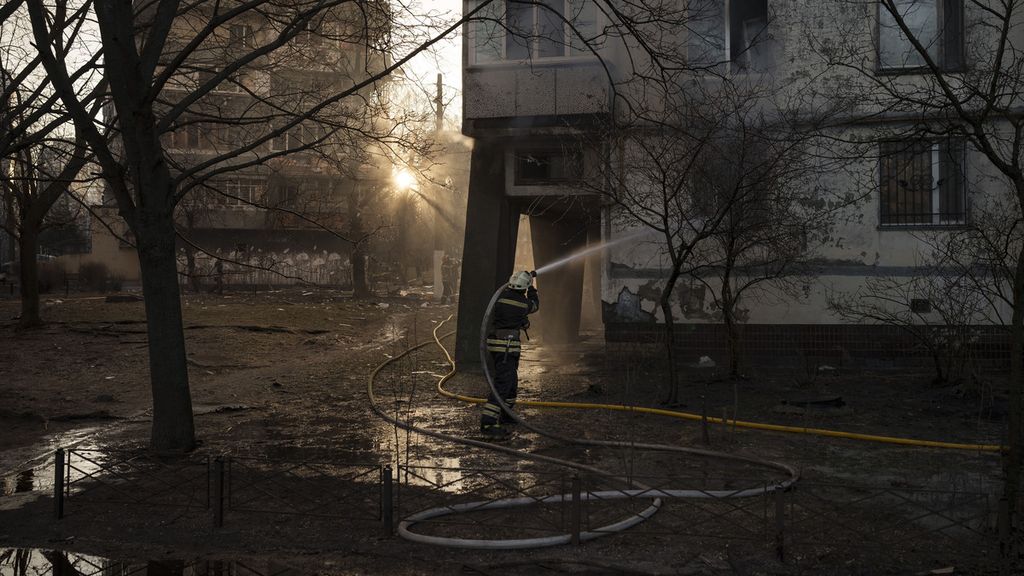 Petugas pemadam kebakaran menyemprotkan air untuk memadamkan api yang membakar apartemen di Kiev, Ukraina, Selasa (15/3/2022). Kebakaran ini terjadi setelah peluru artileri dari tentara Rusia mengenai apartemen ini,