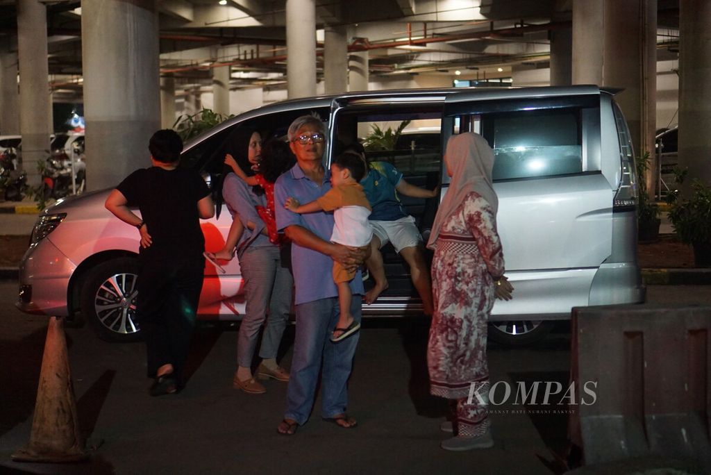 Riki (62) bersama keluarganya memutuskan keluar dari mobil saat menunggu antrean untuk masuk ke kapal di Dermaga Eksekutif Pelabuhan Merak, Banten, Sabtu (6/4/2024) malam.