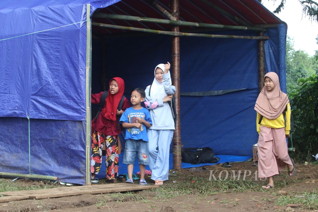 Sejumlah anak keluar dari tenda darurat di Desa Cijedil, Kecamatan Cugenang, Kabupaten Cianjur, Jawa Barat, setelah belajar bersama, Sabtu (17/12/2022) siang.