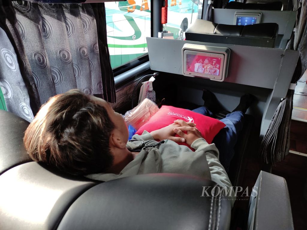 Penumpang kelas <i>sleeper</i> Kencana menikmati tayangan televisi menjelang keberangkatan bus tersebut di Jakarta, Jumat (15/12/2023).
