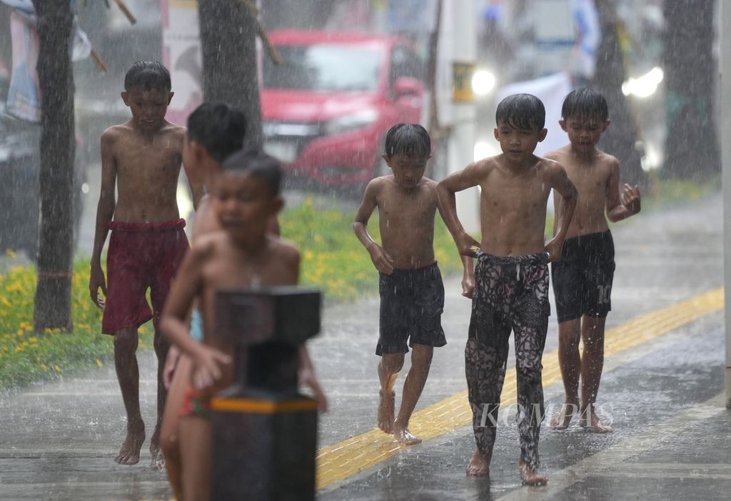 Anak-anak sedang bermain air hujan saat terjadi hujan yang mengguyur DKI Jakarta, di Jalan Penataran, Jakarta Pusat, Kamis (11/1/2024). 