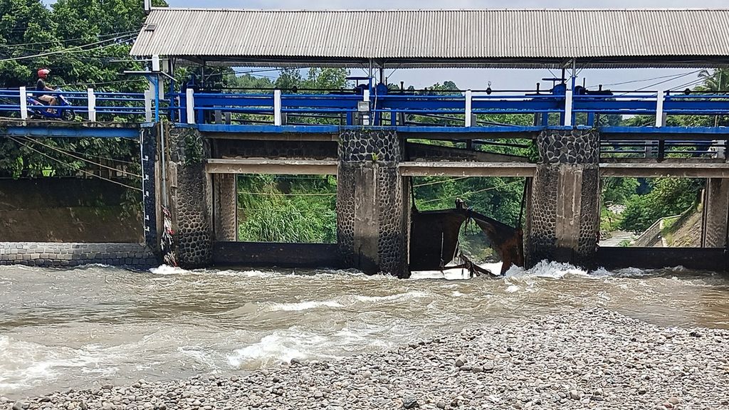 Pengendara sepeda motor melihat di jembatan Bendung Katulampa, Sabtu (6/4/2024). Di bawah jembatan tampak salah satu pintu Bendung Katulampa rusak karena hantaman material kayu yang terbaru arus deras pada Jumat (5/4/2024).