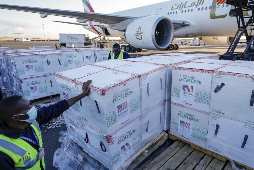 Pekerja bandara berdiri di samping kotak berisi vaksin Moderna di bandara di Nairobi, Kenya, Senin (23/8/2021). Sebanyak 880.460 dosis vaksin Moderna dari total 1,76 juta dosis yang disumbangkan oleh Pemerintah AS melalui fasilitas Covax tiba di Kenya. 