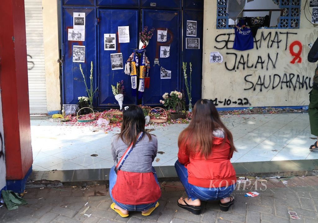 Two women pray in front of the stadium door that witnessed the Kanjuruhan tragedy that killed at least 130 people after the Arema FC match against Persebaya at the Kanjuruhan Stadium, Kepanjen, Malang, Tuesday (4/10/2022).