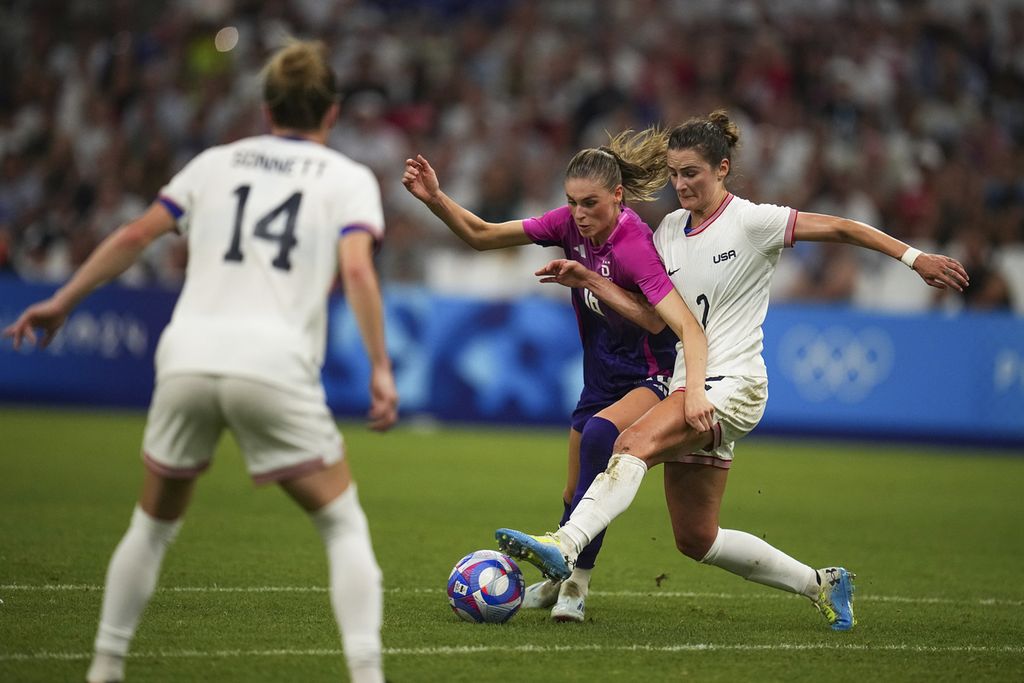 Pemain Jerman Jule Brand (tengah) dan pemain Amerika Serikat, Emily Foc (kanan), berebut bola dalam pertandingan penyisihan Grup B sepak bola putri Olimpiade Paris 2024 di Stadion Velodrome, Marseille, Perancis, Minggu (28/7/2024) atau Senin dini hari WIB. 