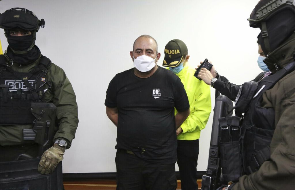 Polisi mengawal ketat Dairo Antonio Usuga alias Otoniel gembong narkotika yang berhasil ditangkap dalam sebuah operasi militer saat tiba di Bogota, Kolombia, Sabtu (23/10/2021). Operasi penangkapan ini merupakan keberhasilan besar Kolombia dalam memerangi kartel narkoba yang terlibat dalam aktivitas korupsi, pembunuhan dan intimidasi.