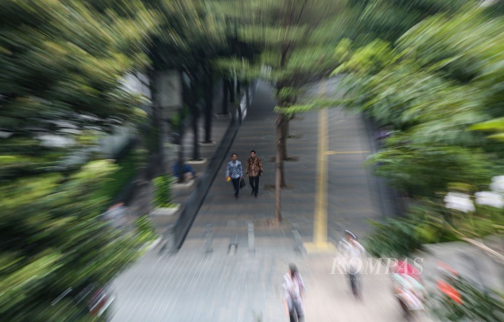 Employees walk along the pedestrian area on Jenderal Sudirman Street in Jakarta during their lunch break on Tuesday (21/11/2023).